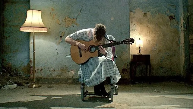 Still from the Hi Ren music video: Ren playing guitar alone in a derelict room