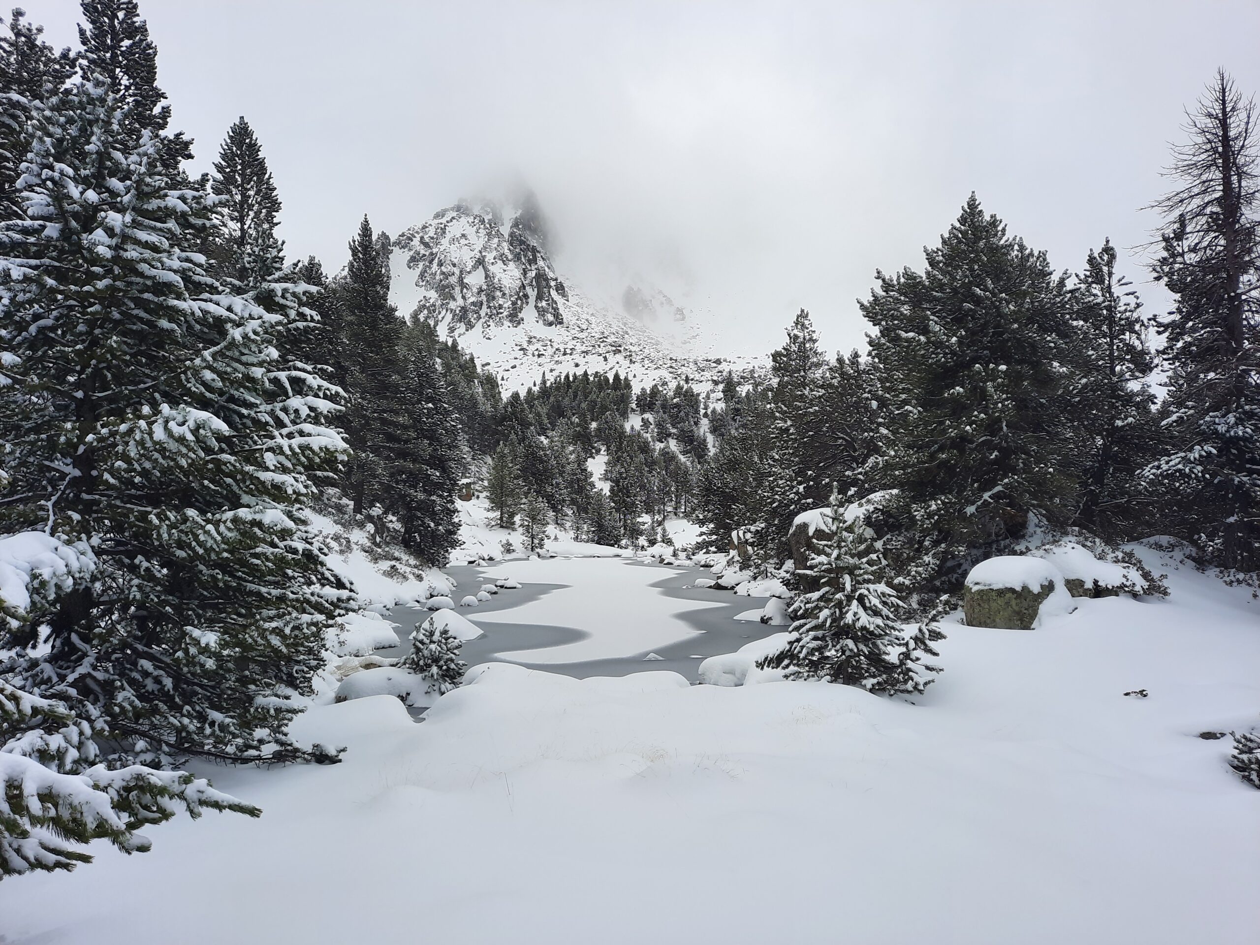 Photo of a small snow-covered lake beside Estany Moreno in the mountains of Andorra.